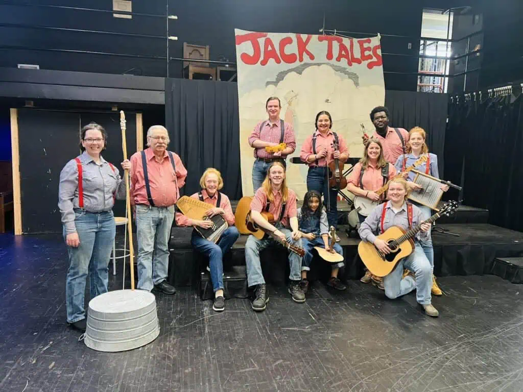 The Jack Tale Players in costume holding their instruments in front of an artistic banner.