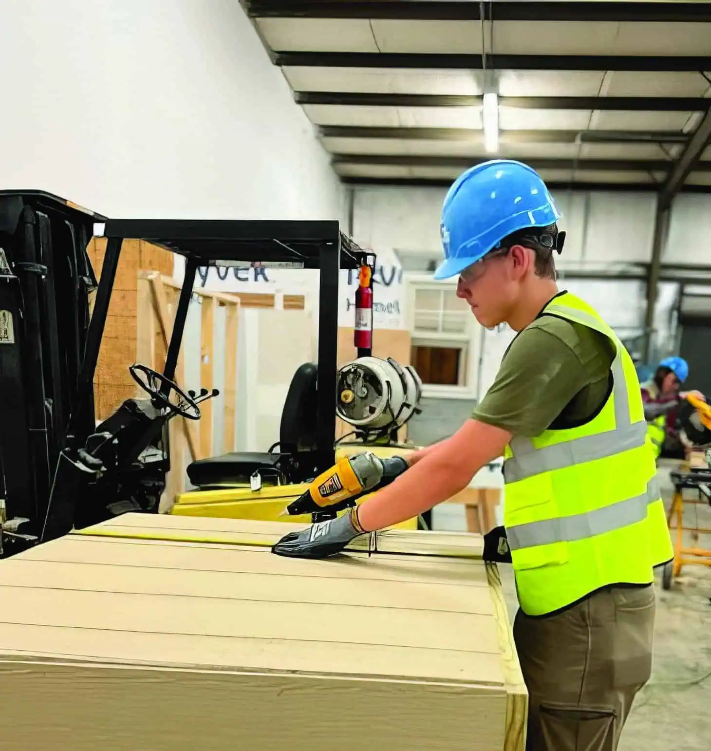 A student is measuring to ensure the project is being built correctly and to standards, while wearing his protective equipment.