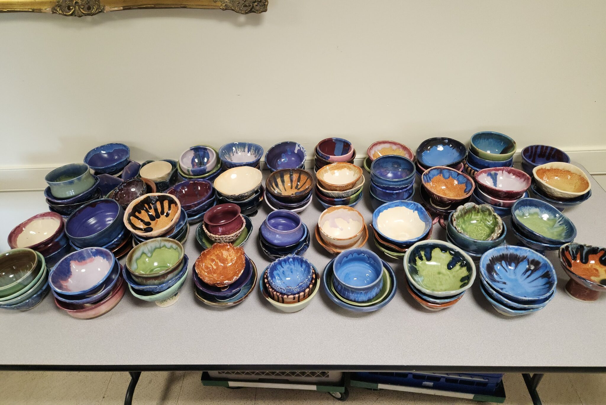 Colorful clay bowls in rows and piles on a table to be sold at Ferrum College Empty Bowls 2025