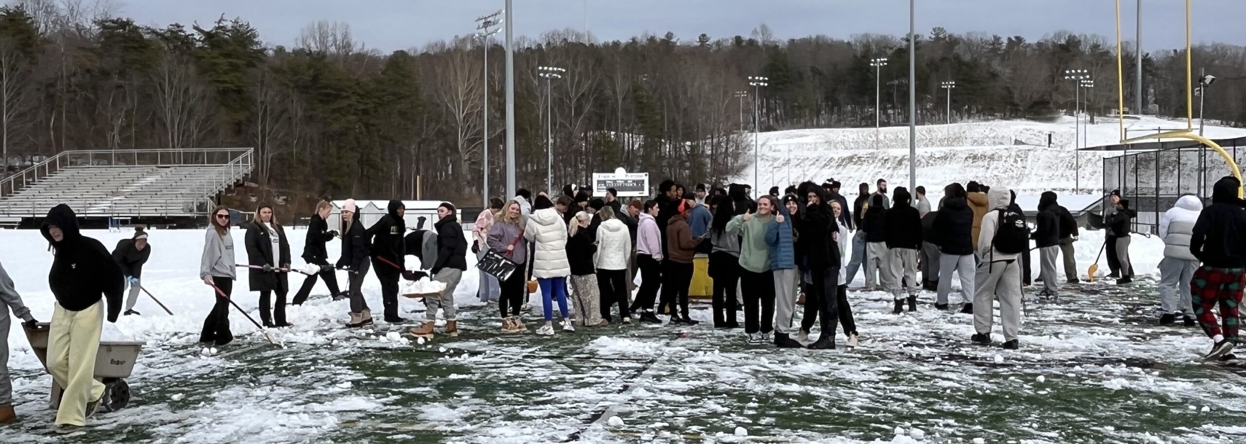 Ferrum student-athletes shoveling the snow and ice off the field.