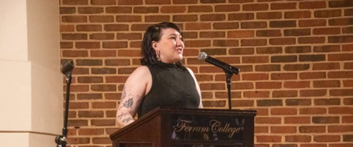Student in black outfit at Ferrum College podium in front of brick wall