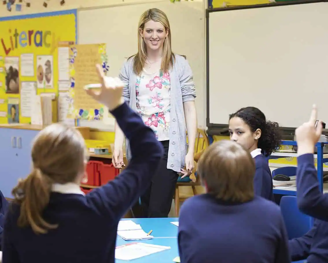 Teacher smiling while standing in front of a group of students.