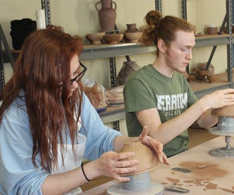female and male students creating bowls in clay studio